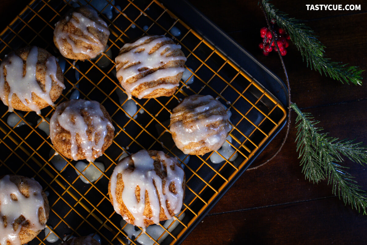 Cinnamon bun cookies with a cream cheese glaze on a golden cooling wrack 